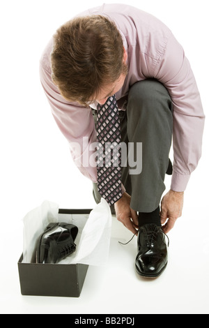 Man dressed in business attire trying on a new pair of dress shoes Isolated on white  Stock Photo