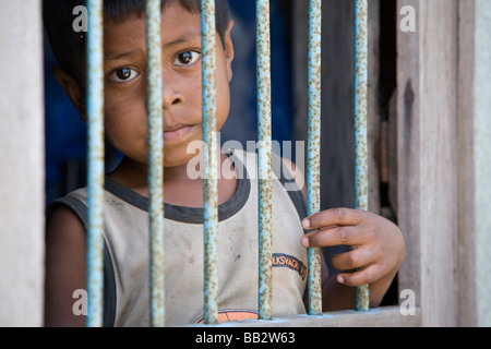 Daily Life in Bangladesh; A boy looks through the bars of his front door in Bangladesh. Stock Photo