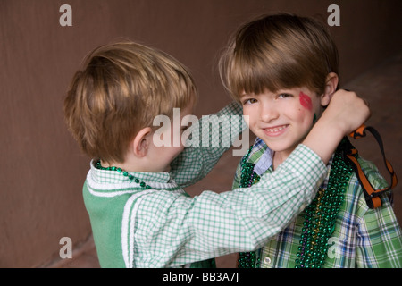 USA; Georgia; Savannah.  Two young boys exchanging beads on St. Patrick's Day.  (MR) Stock Photo