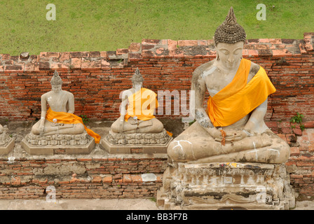 THAILAND, Ayutthaya. Statues of sitting buddhas wearing orange golden clothes around the chest, meditating at Ayutthaya Stock Photo