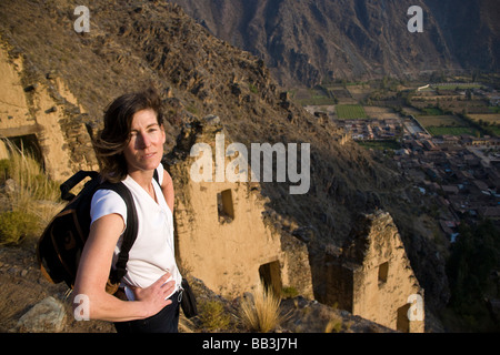 Hiker in front of Aztec granary with town below, Ollantayambo, Peru. Stock Photo