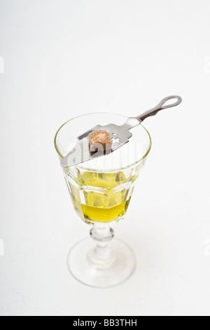 Absinthe glass with a perforated absinthe spoon topped with a piece of raw sugar. Stock Photo