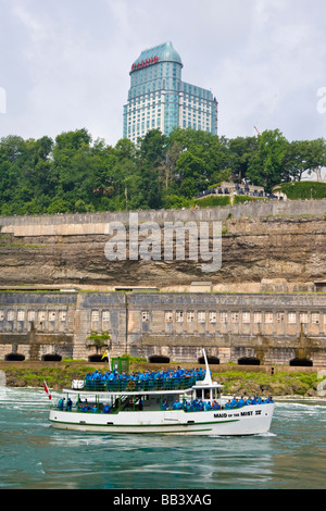 Canada, Ontario, Niagara Falls. Maid of the Mist sightseeing boat on Niagara River passes casino in background. Stock Photo