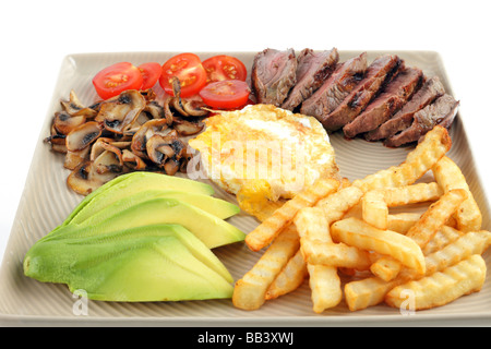 Steak dinner with egg and chips tomato avocado mushrooms Stock Photo