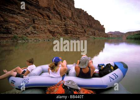 USA, Utah, Canyonlands National Park. Boaters relax in inflatable kayak tied to raft on Colorado River. MR Stock Photo