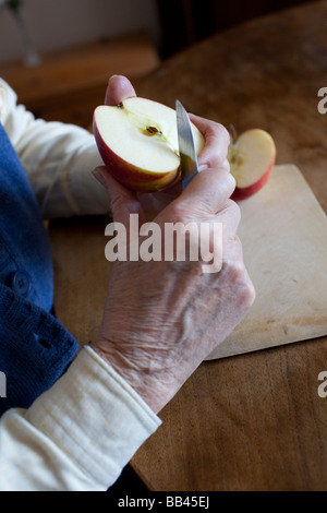 Senior is cutting an apple Stock Photo