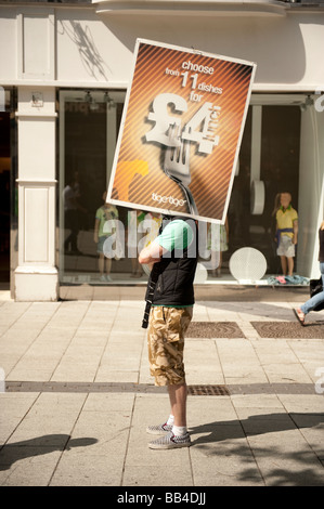 Man employed on minimum wage to hold an advertising banner in the street Cardiff City centre Wales UK Stock Photo