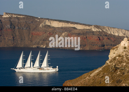 Europe Greece Santorini Thira Oia. Four-masted luxury yacht Windstar entering the bay with Thirasia Island cliffs in background Stock Photo