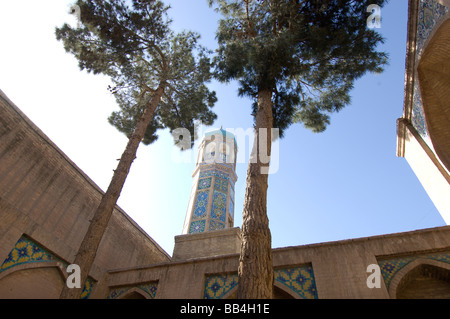 A tiled minaret rises over a courtyard shaded by pine trees, in the oldest part of the Friday Mosque or Stock Photo