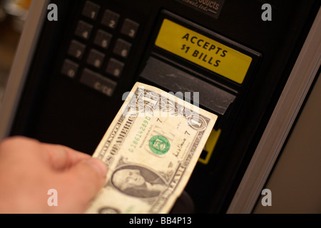 Putting money into a candy vending machine Stock Photo