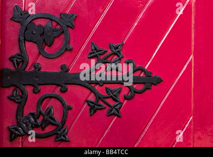 Europe, Ireland, Ennis. A decorative black hinge on a bright red door of the new Franciscan Friary for monastics. Stock Photo