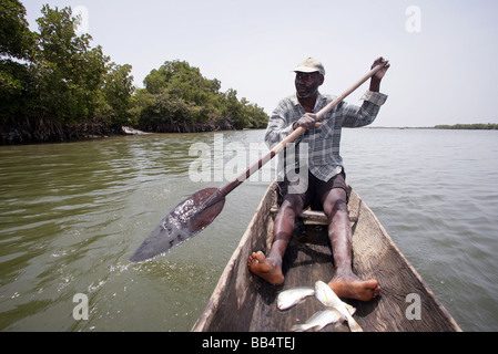 Senegal: Fisherman in his dugout canoe on the river Casamance Stock Photo