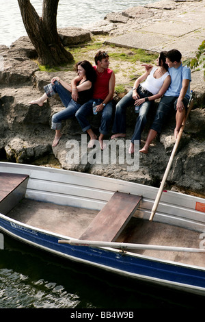two couples sitting at lakeside in front of a rowboat Stock Photo
