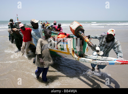 Fishermen bring a boat up onto the shore at Kap Skirring, Senegal Stock Photo