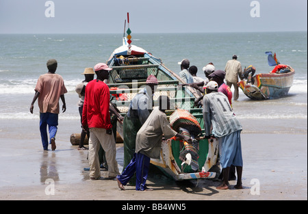 Fishermen bring a boat up onto the shore at Kap Skirring, Senegal Stock Photo