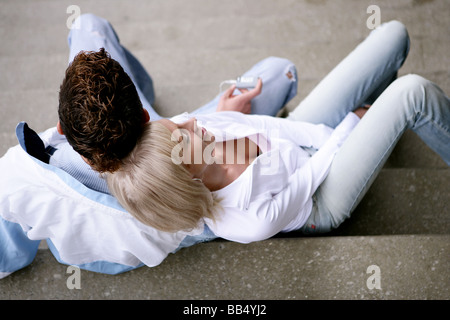 teenager couple with mp3 player sitting on stairs Stock Photo