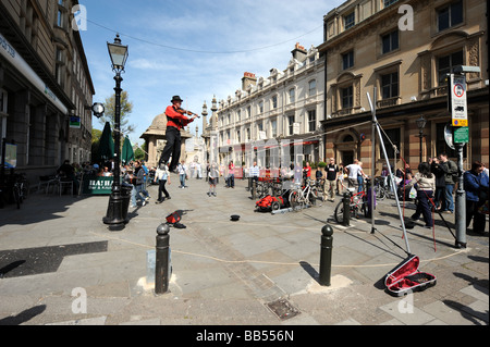 A busker plays a violin while balancing on a tightrope in Brighton city centre Stock Photo