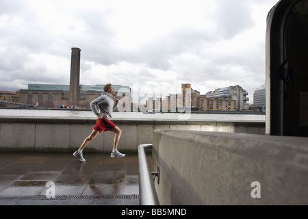 Man joggin along the Thames with the Tate Modern in the background