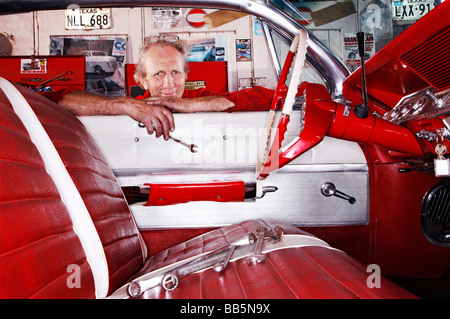 Kent, UK, portrait of mechanic in garage leaning over car window Stock Photo