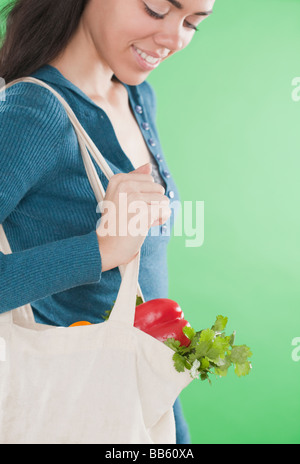 Hispanic woman carrying reusable bag of vegetables Stock Photo
