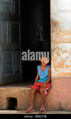 Cuban boy sitting on door step, Trinidad, Cuba Stock Photo