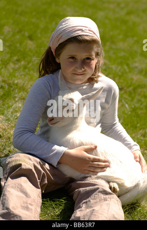 Girl hugging goats in grass Stock Photo