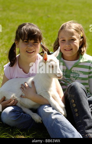 girl holding a goat in his arms on the meadow Stock Photo