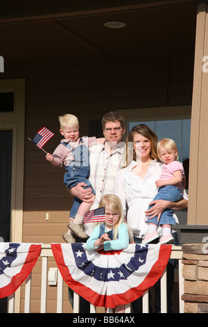 Patriotic family on front porch with children waving flags Stock Photo