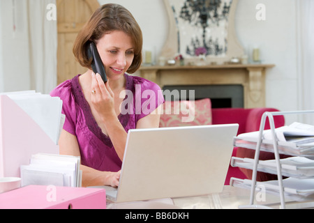 Woman using laptop and talking on phone Stock Photo