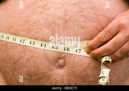 Obese Man Measuring His Waist With a Tape Measure Stock Photo