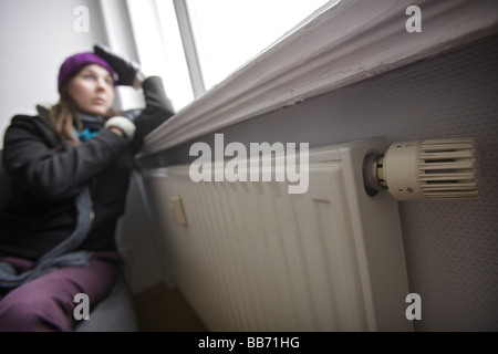 Saving heating coasts young woman at home wearing a cap and gloves Stock Photo