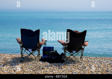 Two people soak up the sun on the beach Stock Photo