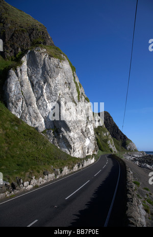 The A2 causeway coastal route coast road at Garron Point under Limestone and basalt cliffs County Antrim Northern Ireland UK Stock Photo