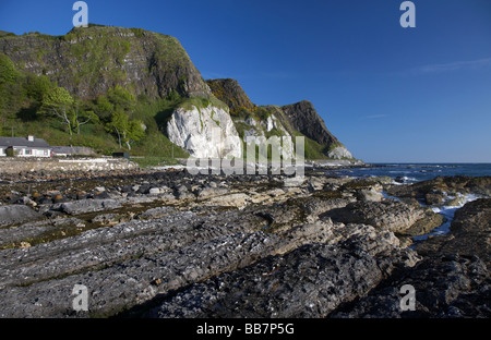 The A2 causeway coastal route coast road at Garron Point under Limestone and basalt cliffs with basalt rock formations Stock Photo