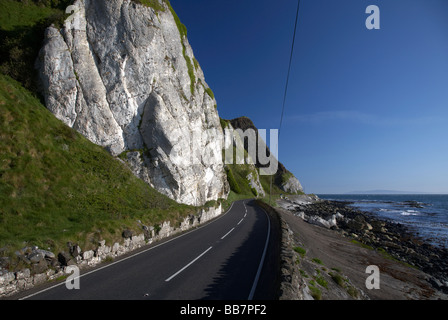 The A2 causeway coastal route coast road at Garron Point under Limestone and basalt cliffs County Antrim Northern Ireland ni UK Stock Photo