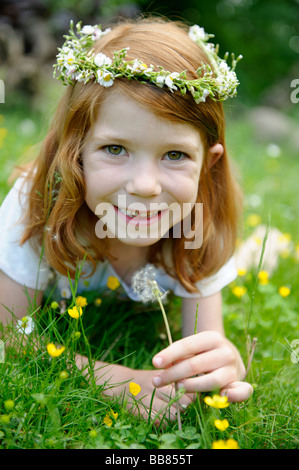 Young girl wearing a floral wreath in her hair holding a dandelion clock Stock Photo