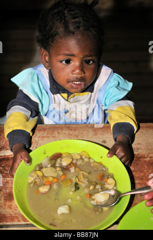 Small, dark skinned, cross-eyed girl in a soup kitchen, slums of Alto de Cazuca, Soacha, Bogotá, Columbia Stock Photo