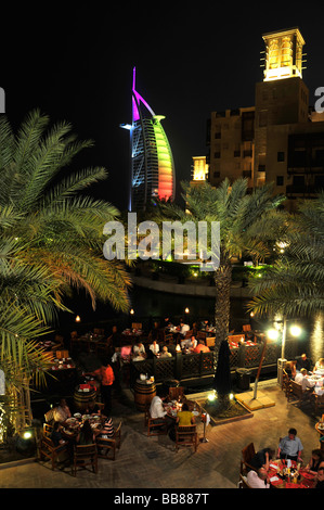 Open-air restaurant at the Madinat Jumeirah resort in front of the illuminated facade of the seven-star hotel Burj al Arab, Ara Stock Photo