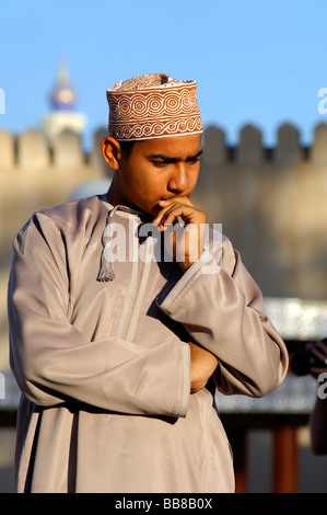 Omani boy in the national costume dishdasha and a kummah cap, lost in thought, Nizwa, Sultanate of Oman Stock Photo