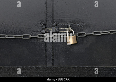 Metal door secured by bar with padlock and chain Stock Photo