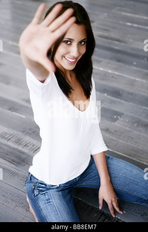 Portrait of young smiling kneeling beautiful woman streching hand Stock Photo