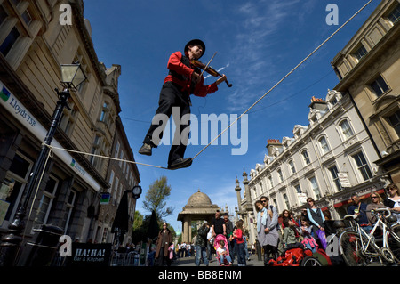 A Street Theatre busker plays a violin while balancing  on a tightrope during Brighton Festival Stock Photo