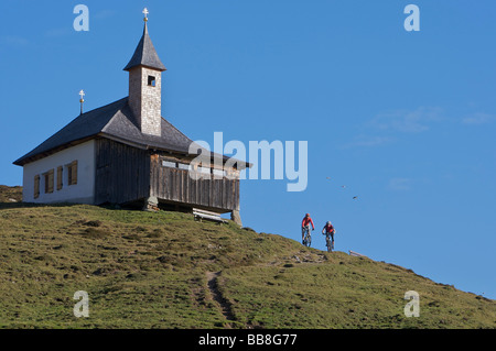 Mountain biker at Kobinger chapel above Harlasanger alp, Rettenbach, Tyrol, Austria Stock Photo