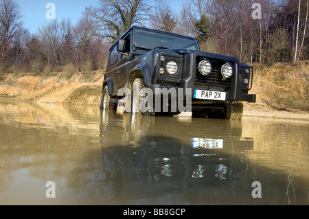 A Landrover Defender driving through a flood on an off road exercise Stock Photo