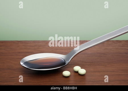 Loeffel mit Hustensaft und Tabletten Spoon with cough mixture and tablets Stock Photo