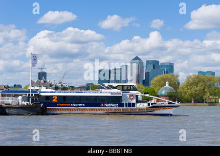 Greenwich pier with with river Thames Clipper catamaran passenger boat & dome of pedestrian tunnel & canary wharf in background Stock Photo