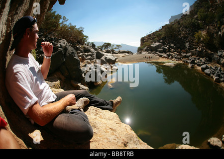 Sitting by the hidden lake near the deserted village of Sab Bani Khamis in Jebel Shams in Oman Stock Photo