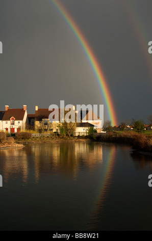 Dramatic black sky with double rainbow and reflected in pond Northern France Stock Photo