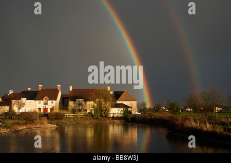 Dramatic black sky with double rainbow and reflected in pond Northern France Stock Photo