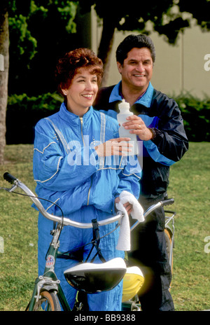 Hispanic Latin couple ride tandem bike sport exercise drink cool rest safety helmet bicycle health Stock Photo